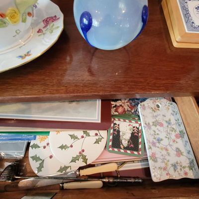 Assorted vintage tableware and collectibles, including a light blue art glass vase, floral porcelain saucer, and a drawer filled with...