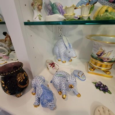 Collection of Herend porcelain figurines, featuring blue fishnet pattern rabbits and a wolf, displayed alongside other decorative...