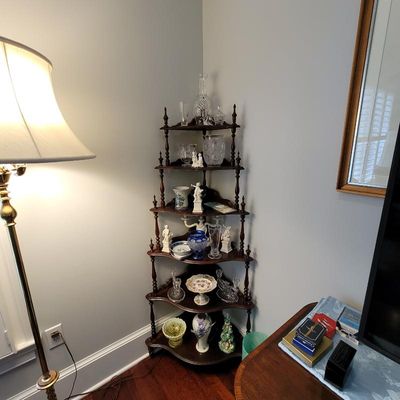 Vintage six-tier dark wood corner whatnot shelf displaying various glassware, porcelain figurines, and decorative collectibles.
