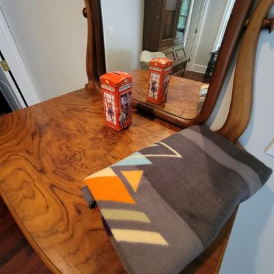 Vintage wooden vanity table with an attached mirror, featuring a folded Pendleton-style wool blanket and a novelty red telephone booth...