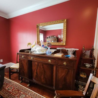 Antique mahogany sideboard with brass hardware and claw-and-ball feet, displaying various ceramic tureens, glassware, and a large...