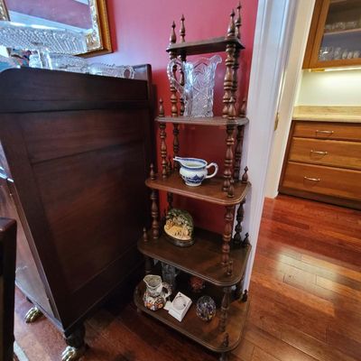 Vintage five-tier wooden corner whatnot shelf with turned spindle supports, displaying various decorative glassware and ceramic items.