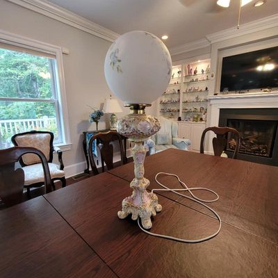 Vintage Gone with the Wind style hurricane lamp featuring a hand-painted floral globe and an ornate pink and gold ceramic base.
