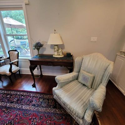 Traditional wingback armchair in light blue and cream striped upholstery, paired with a dark wood console table featuring cabriole legs.