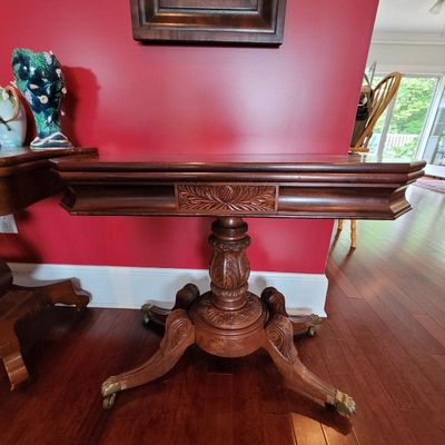 Antique mahogany card table featuring a carved pedestal base with four scrolled legs on brass casters and a decorative pineapple motif on...