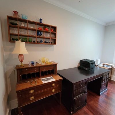 Vintage wooden secretary desk with brass hardware, paired with a dark wood double-pedestal executive desk and a wall-mounted shadow box...