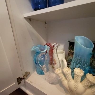 Collection of vintage glassware, including a clear cut-glass pitcher, a blue opalescent glass pitcher, and a white Fenton epergne base,...