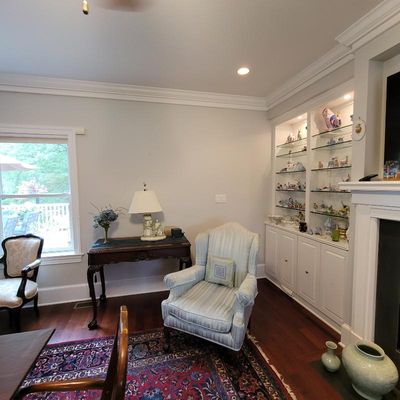 Traditional living room furniture including a light blue striped wingback armchair, a dark wood console table with a table lamp, and a...