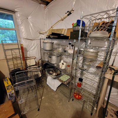 Assorted wire shelving units holding kitchenware, including large aluminum stockpots, baking pans, and a hummingbird feeder.