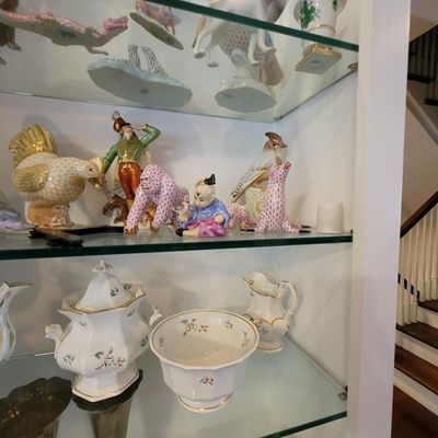 Collection of Herend porcelain figurines, including a pink fishnet gorilla and seal, displayed alongside a white and gold floral tea set...