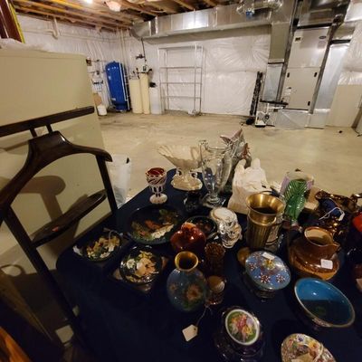 Assortment of vintage glassware, ceramics, and decorative items displayed on a table, including a brass vase, a glass pitcher, and...