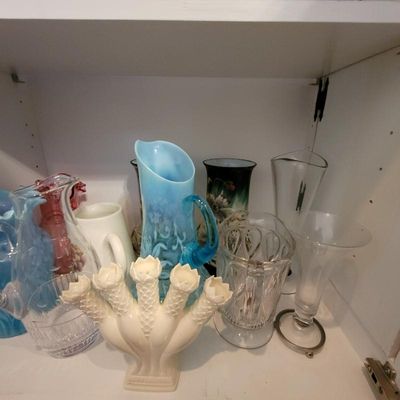 Collection of vintage glassware, featuring a Fenton milk glass epergne vase, a blue opalescent glass pitcher, and various clear and...