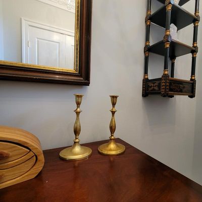 Pair of vintage brass candlesticks with a classic baluster stem design, displayed on a wooden tabletop.
