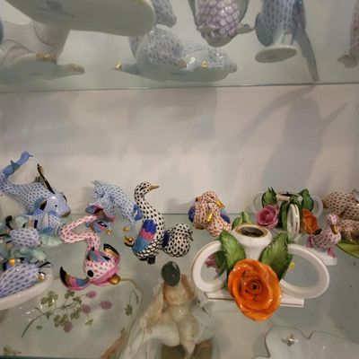 Collection of Herend porcelain figurines, including various hand-painted fishnet pattern animals and floral-decorated pieces, displayed...