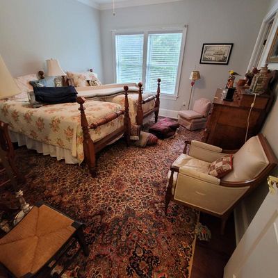 Traditional bedroom set featuring a pair of wooden four-poster twin beds with floral quilts, a matching wooden dresser, a vintage...