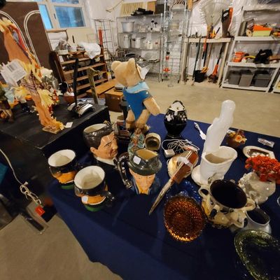 Assorted vintage collectibles, including character mugs, a Ronald Reagan mug, a plush teddy bear, and various decorative glassware...