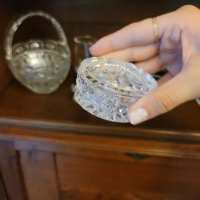 Small vintage cut crystal trinket box with lid, shown alongside other glassware on a wooden shelf.