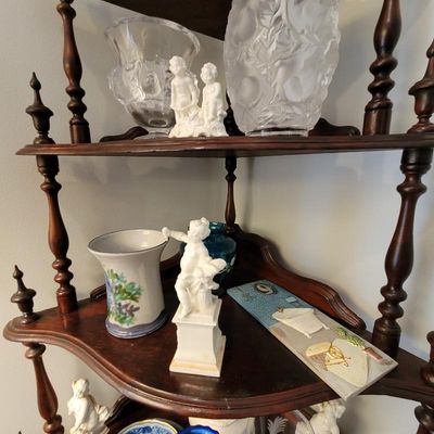 Vintage wooden corner whatnot shelf displaying various decorative items, including white porcelain cherub figurines, frosted glass vases,...