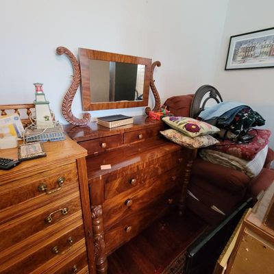 Antique Empire-style mahogany dresser featuring a swivel mirror with carved harp-shaped supports, two glove drawers, and three large...