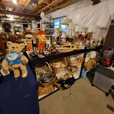 Assorted home decor and collectibles, including a plush teddy bear, autumn scarecrow figures, woven baskets, and various table lamps...