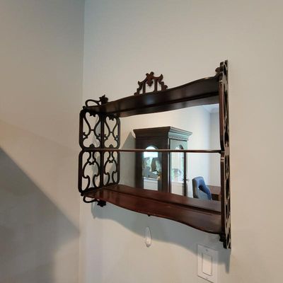 Antique Victorian-style wooden wall shelf with a mirrored back, featuring ornate fretwork side panels and a decorative top crest.
