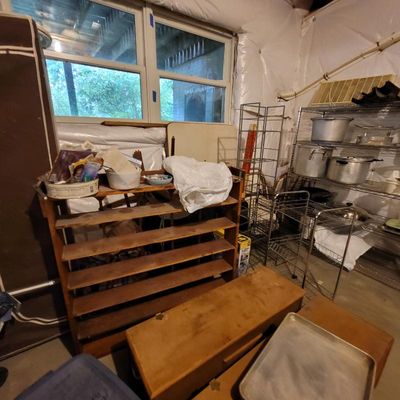 Assorted storage items including a multi-tiered wooden shoe rack, a low wooden bench, and wire shelving units holding metal pots and pans.