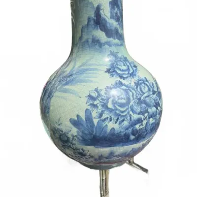 Chinese blue and white crackle-glazed porcelain vase, featuring hand-painted floral and mountain landscapes, mounted on a metal stand.