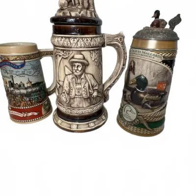Three vintage ceramic beer steins, including a large German-style stein with a hunter figurine lid, a Ducks Unlimited mallard-themed...