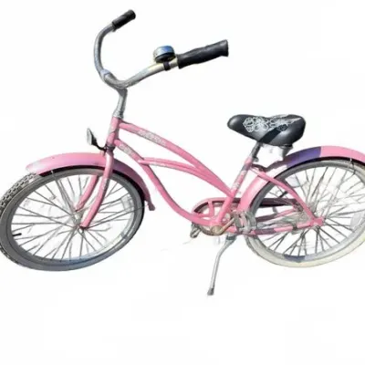 Pink cruiser-style bicycle featuring a step-through frame, matching fenders, a black patterned seat, and a handlebar bell.