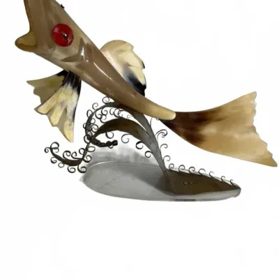 Vintage mid-century carved horn fish sculpture with a red eye, mounted on a decorative metal stand.