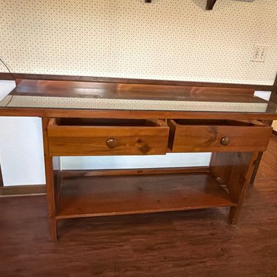 Rustic pine console table featuring a glass top protector, two drawers with wooden knobs, and a lower display shelf.