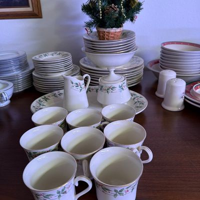 Sale Photo Thumbnail #150: Lenox Holiday porcelain dinnerware set featuring a holly and berry motif with gold trim, including teacups, saucers, plates, bowls, a creamer, and a sugar bowl.