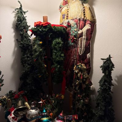 Sale Photo Thumbnail #149: Assorted Christmas decorations, including a large fabric Santa Claus wall hanging, artificial pine trees, garlands, and oversized metallic ornaments.