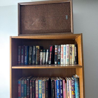 Sale Photo Thumbnail #178: Vintage Pioneer speaker with a woven brown grille cloth, resting atop a wooden bookshelf filled with fantasy and sci-fi paperback books.