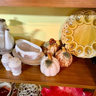 Sale Photo Thumbnail #129: Collection of tabletop decor including a vintage floral porcelain coffee pot, gravy boat, salt and pepper shakers, glazed ceramic decorative pumpkins, and an amber ceramic deviled egg platter.