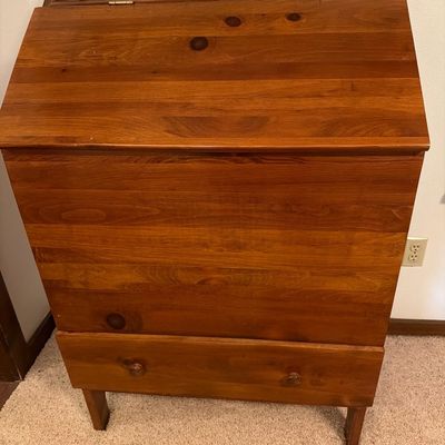 Vintage knotty pine slant-front desk featuring a hinged writing surface and a single bottom drawer with wooden knobs.