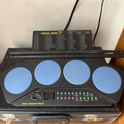 Vintage Yamaha DD-7 Super Session Player electronic drum pad machine with four blue pads, style list panel, and a pair of black...