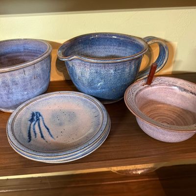 Assorted studio pottery pieces, including a large blue-glazed mixing bowl with a handle and spout, a matching bowl, small plates, and a...