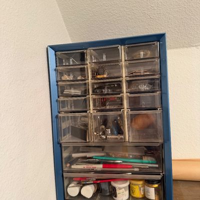 Vintage blue metal multi-drawer organizer cabinet filled with various small tools, hardware, and craft supplies.