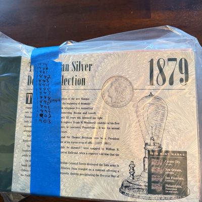 American Silver Dollar Collection coin set, featuring an 1879 Morgan silver dollar, sealed in original plastic packaging with handwritten...