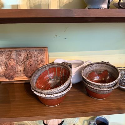 Sale Photo Thumbnail #126: Set of handcrafted stoneware soup bowls with terracotta and speckled glaze, alongside a carved wood gnome wall plaque.