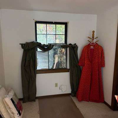 Sale Photo Thumbnail #203: Vintage red quilted robe hanging on a wooden coat rack, alongside olive green drapes and packaged pillows.