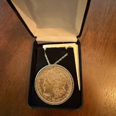 Sale Photo Thumbnail #211: Morgan silver dollar coin pendant necklace in a rope bezel, presented in a black velvet jewelry box.