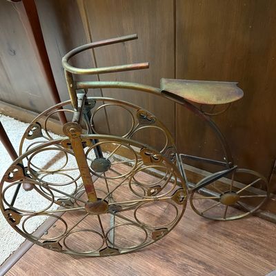 Sale Photo Thumbnail #139: Vintage brass-toned metal wine rack shaped like a high-wheeler bicycle, featuring circular bottle holders within the large front wheel.