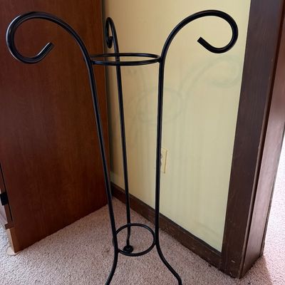 Sale Photo Thumbnail #171: Black wrought iron plant stand featuring three scrolled arms and a tripod base.