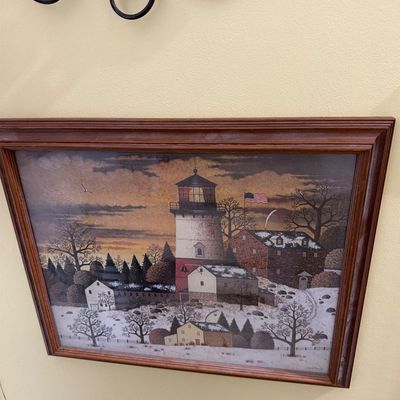 Sale Photo Thumbnail #173: Framed folk art print depicting a snowy lighthouse scene with an American flag, housed in a stained wood frame.