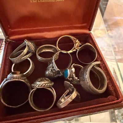 Sale Photo Thumbnail #112: Collection of vintage silver-tone and gemstone rings presented inside a red satin-lined Zales jewelry box.