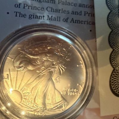 Sale Photo Thumbnail #208: A 1992 American Silver Eagle coin housed in a protective plastic capsule, shown alongside its certificate of authenticity.