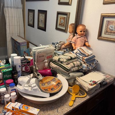 Sale Photo Thumbnail #119: Bathroom counter assortment including folded striped towels, toiletries, white slide sandals, Spinbrush electric toothbrushes, and a vintage baby doll.