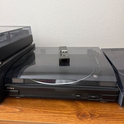 Sony PS-LX47P automatic stereo turntable system with a black finish and clear dust cover, accompanied by a remote control.
